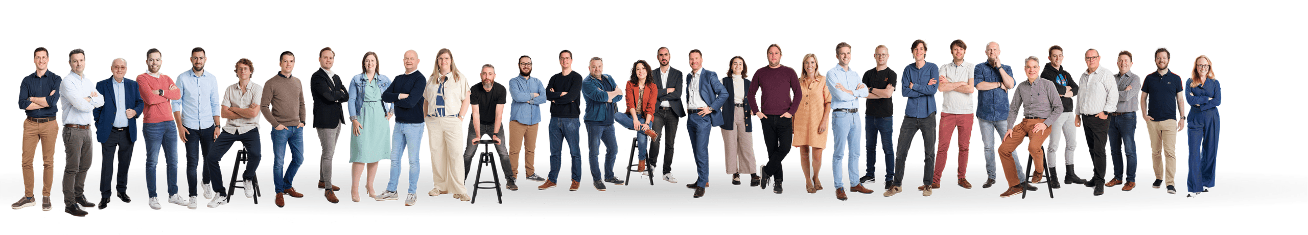 Wide group of diverse professionals posing together in a studio against a white background.